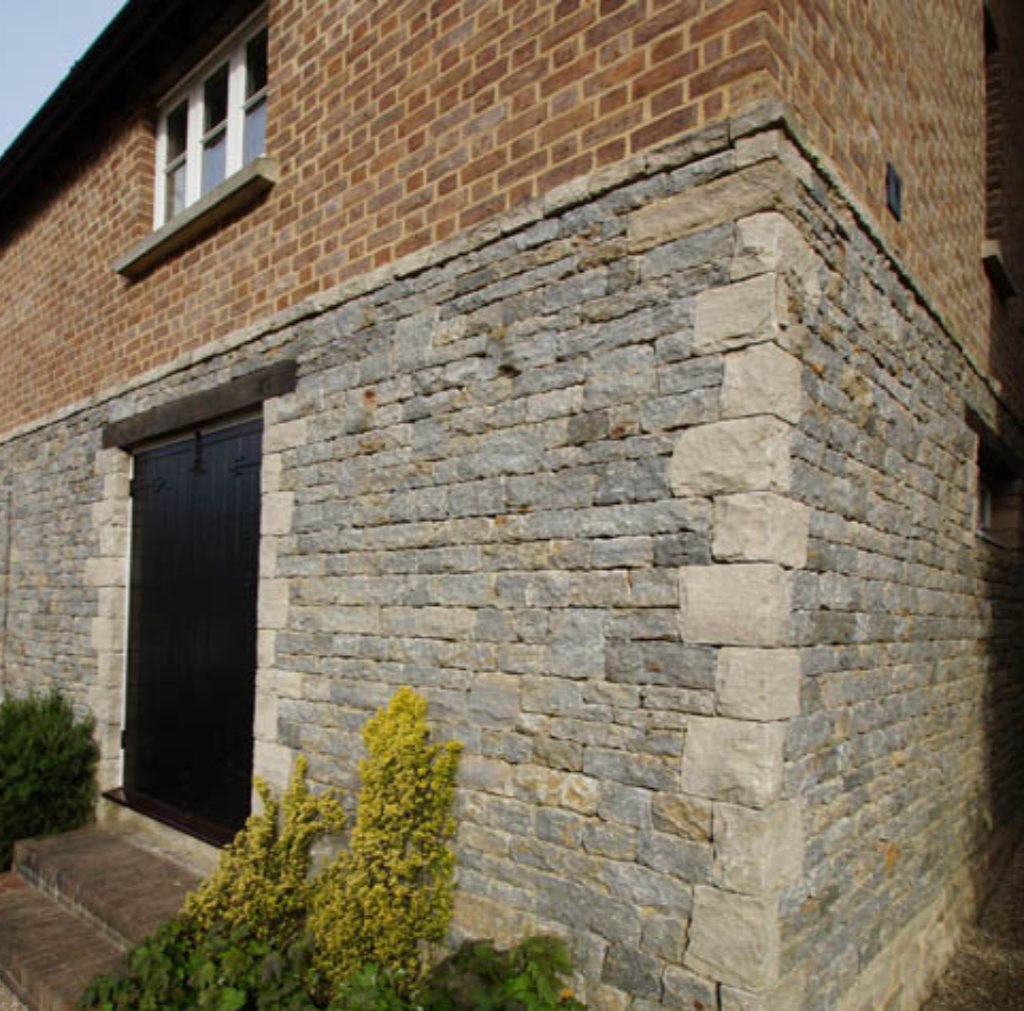 Purbeck dry stone walling on with stone quoins and stone string course