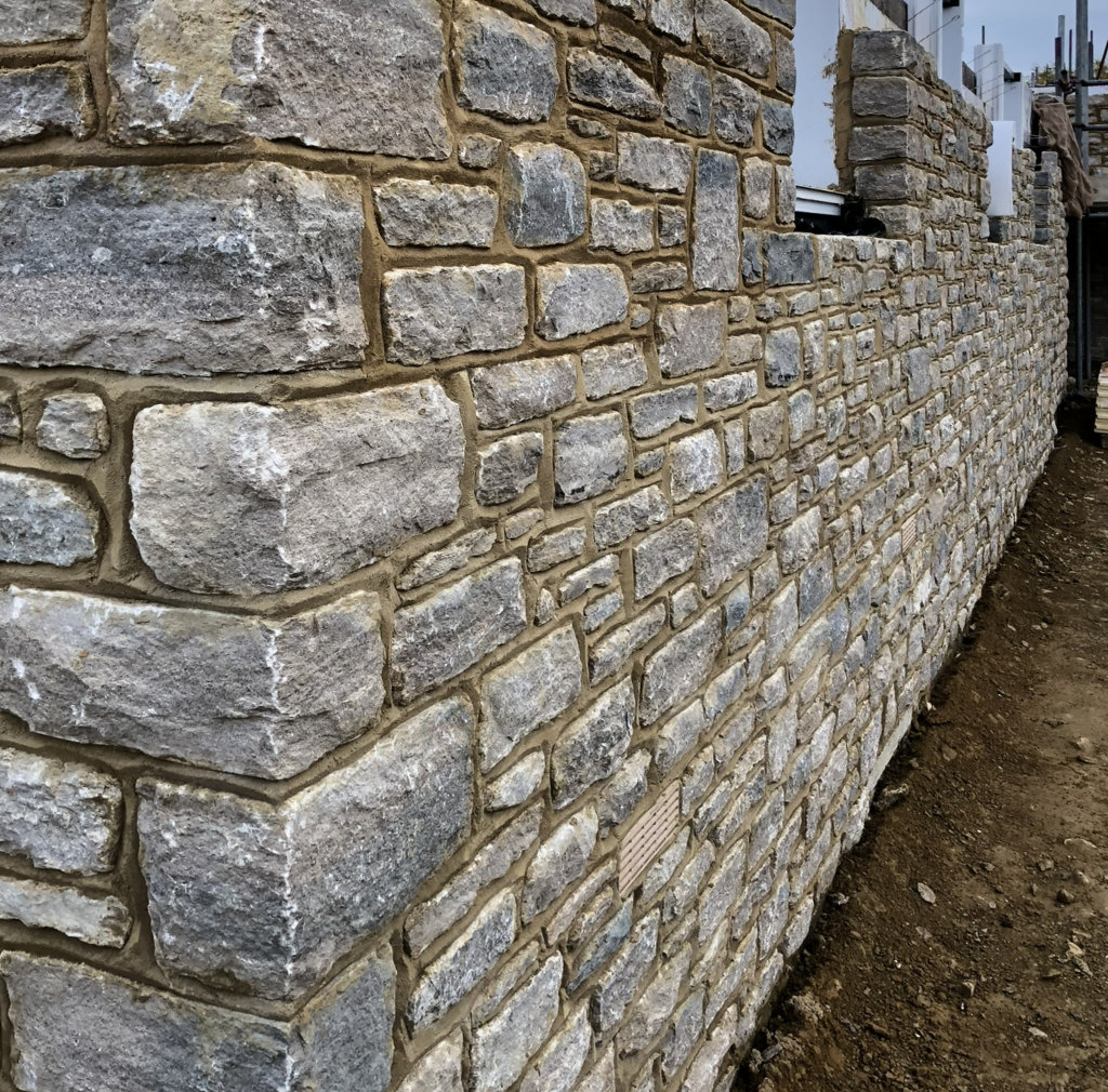 Stone wall construction with arrow head pointing and quoins